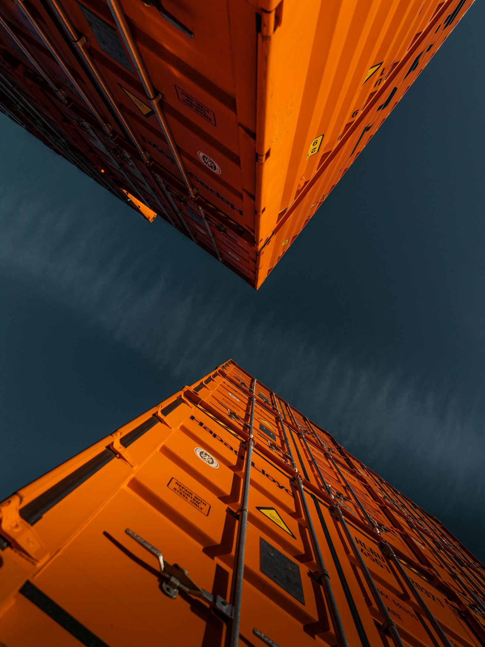 Two orange shipping containers against a dark blue sky